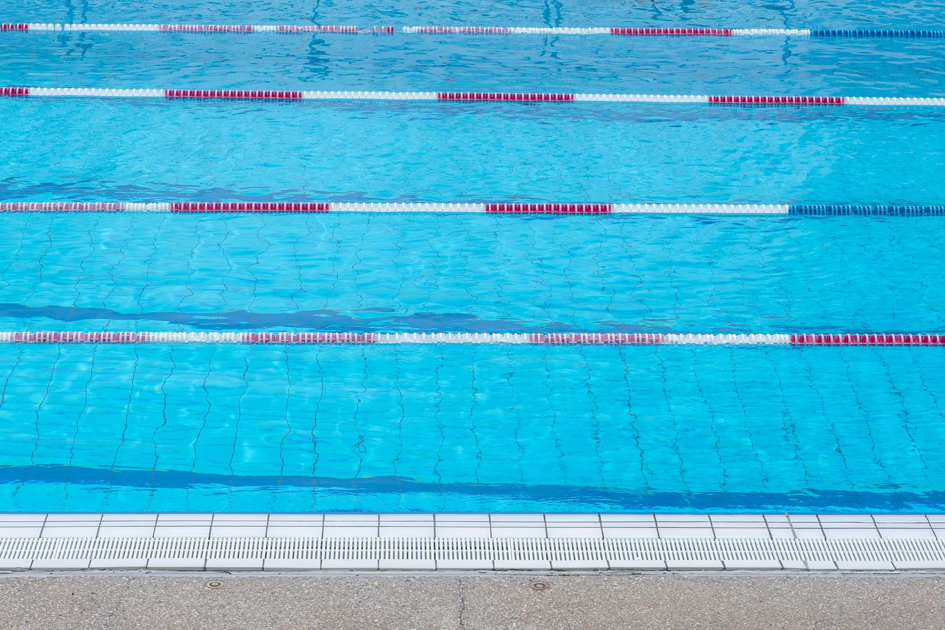 Clear blue water in an outdoor swimming pool with marked swim lanes.