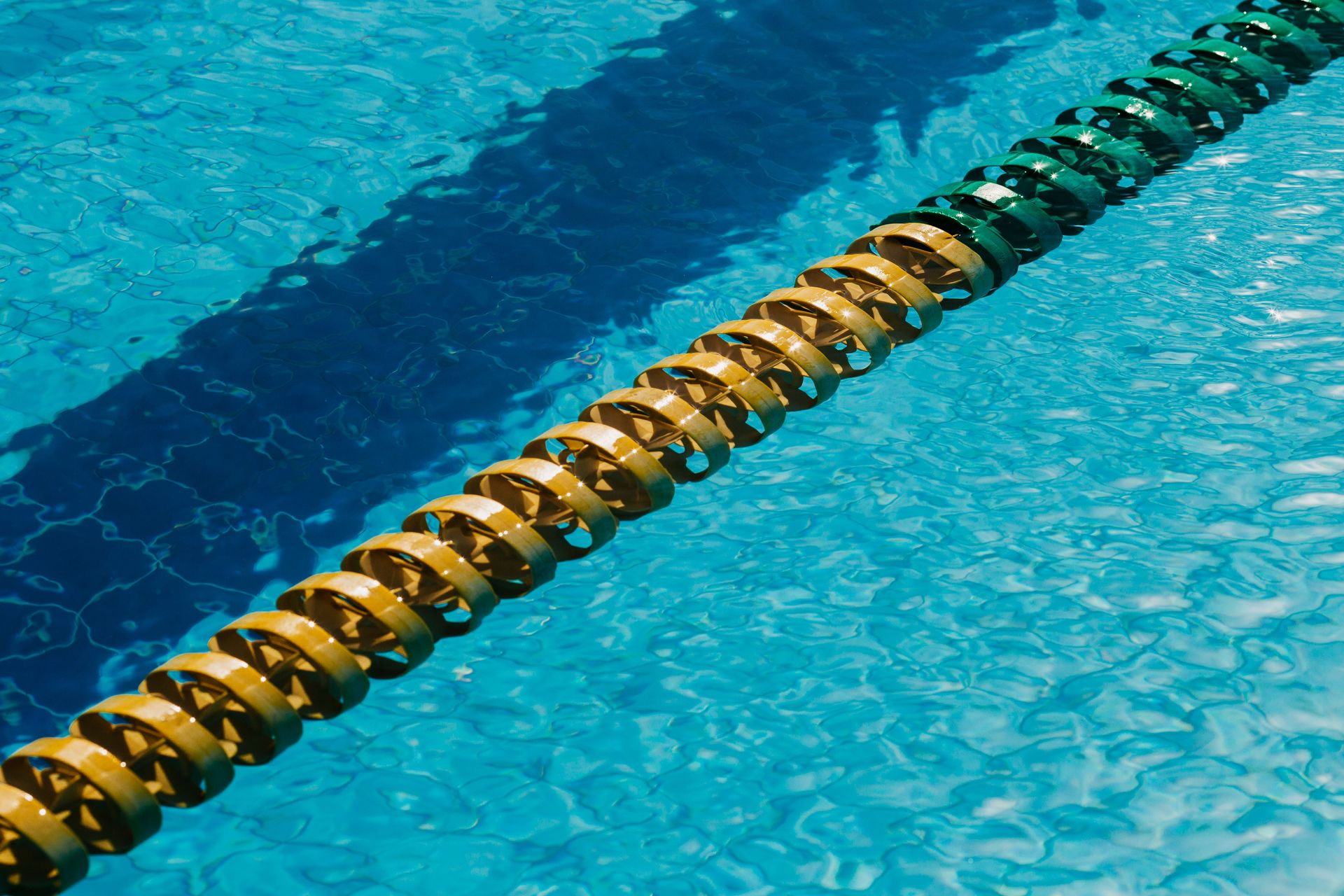 From above of lane marker in rippled blue water in swimming pool on sunny day