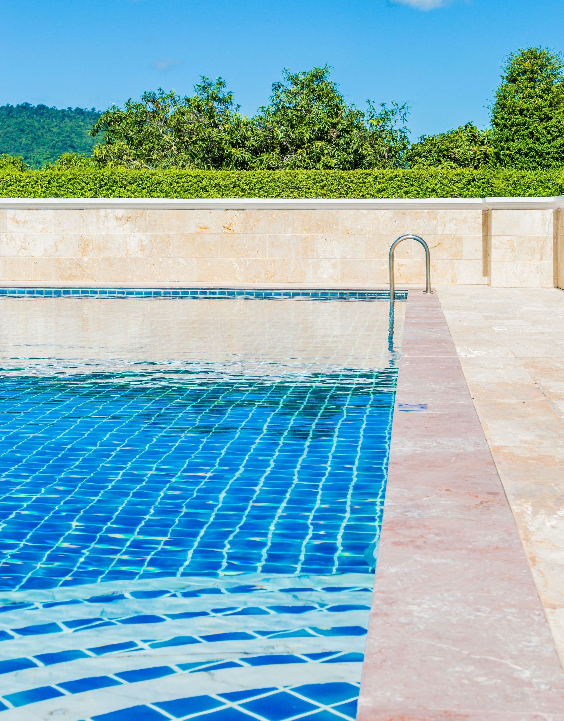Bright and tranquil poolside scene, capturing a turquoise swimming pool under a clear blue sky.