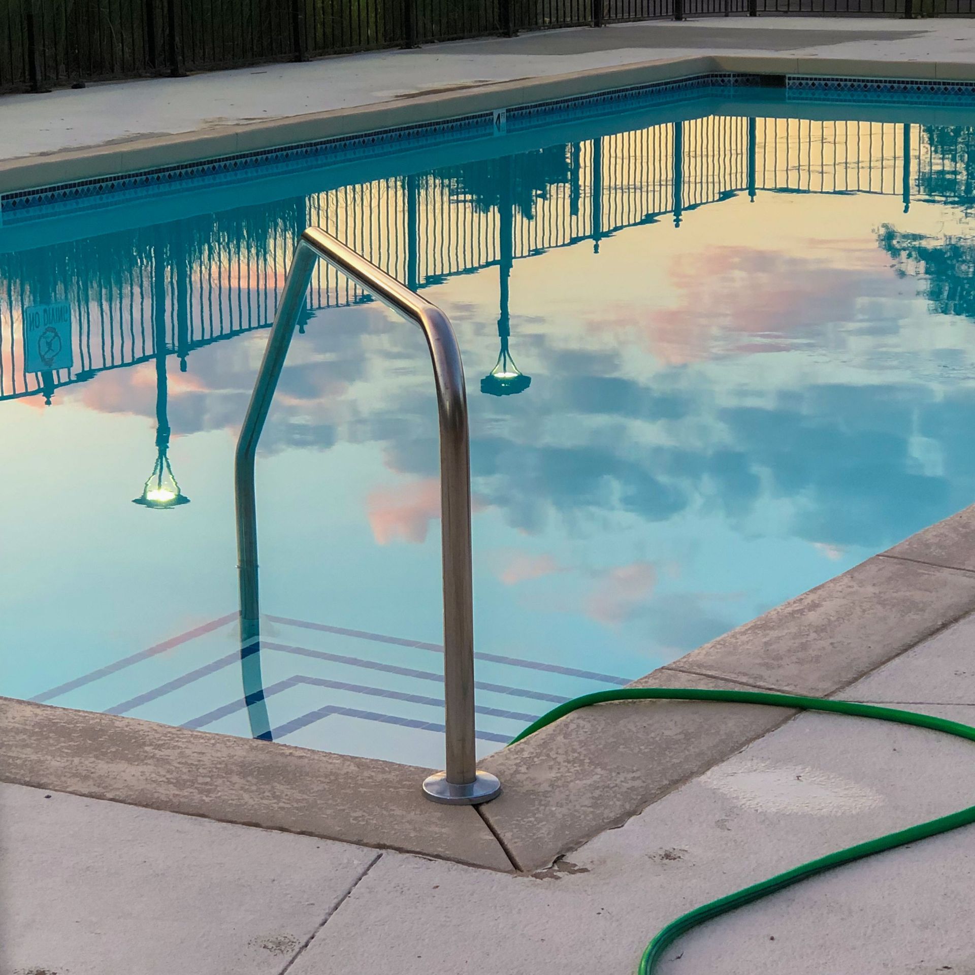 Outdoors swimming pool with calm clean water reflecting pure blue sky in resort